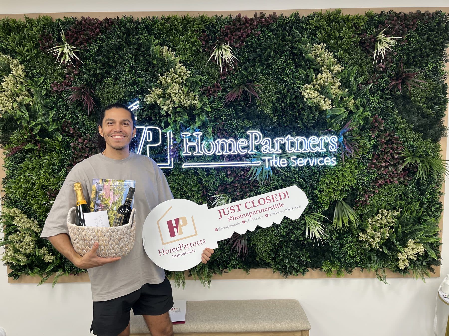 A client holding a Just Closed key and a gift basket at HomePartners Title