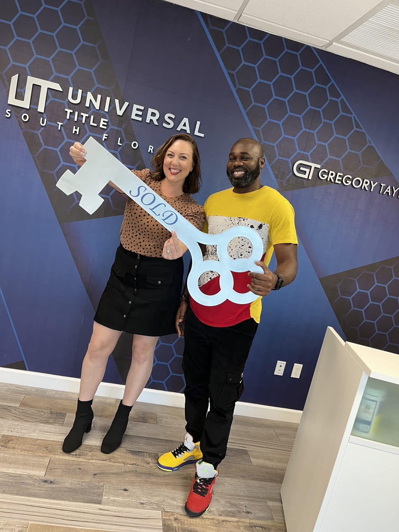 Crystal Creed with a client holding a Sold key sign at the title office