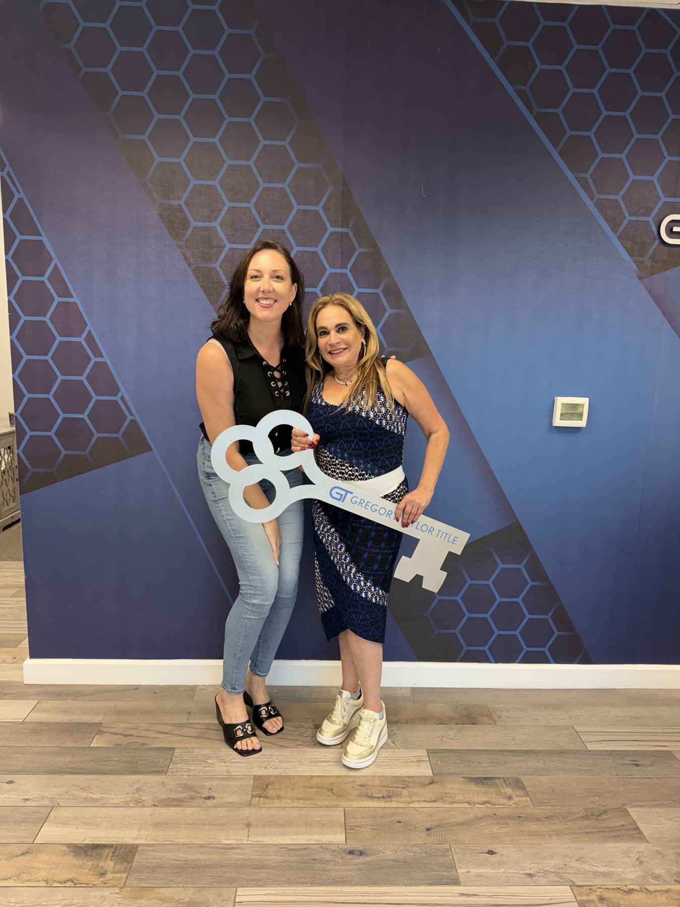 Crystal Creed with a client holding a closing key sign at the title office