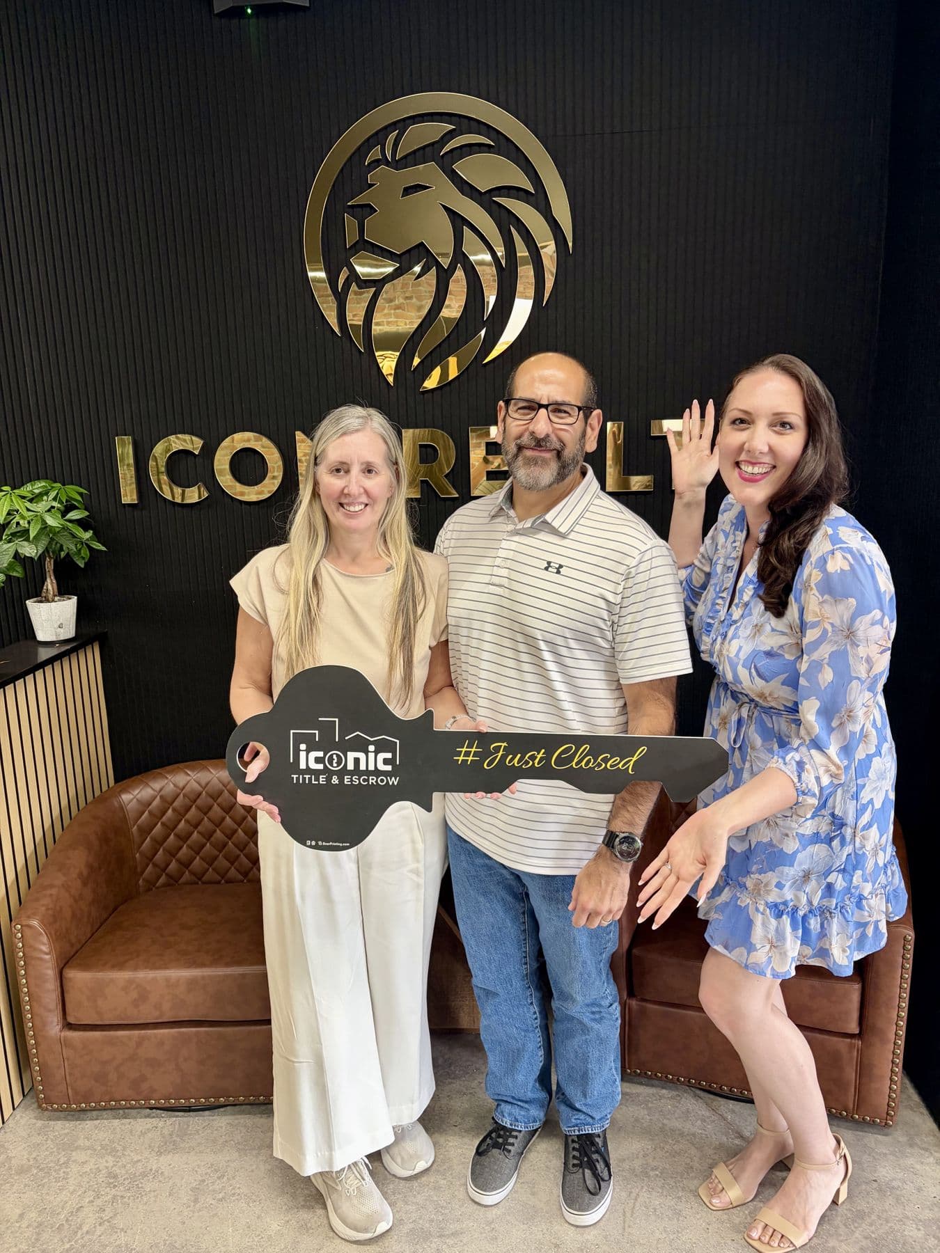 Crystal Creed with clients holding a Just Closed key sign at the Icon Realty office
