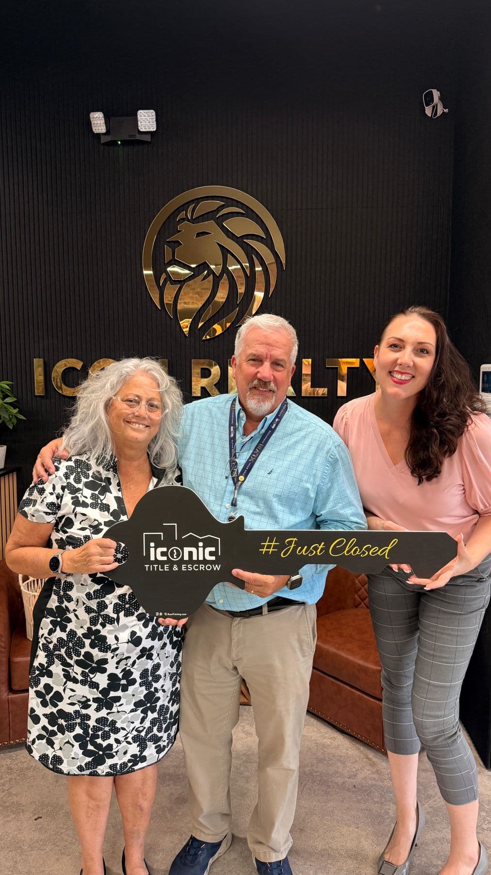 Crystal Creed with clients holding a Just Closed key sign at the Icon Realty office