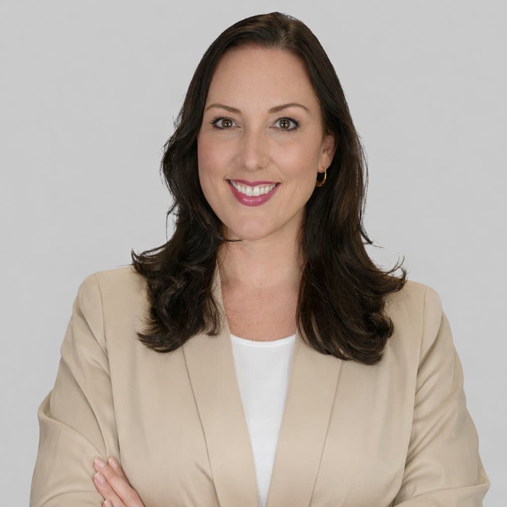 Crystal Creed in a beige blazer, smiling with arms crossed against a light gray backdrop
