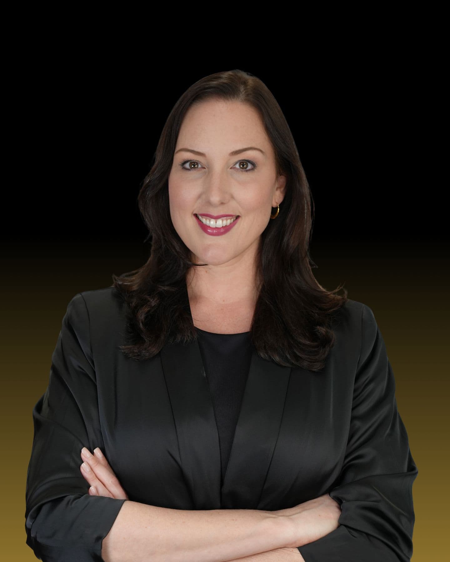 Crystal Creed in a black blazer, smiling with arms crossed against a black to gold backdrop
